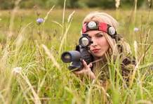 Outdoor laser tag player aiming while crawling through tall grass